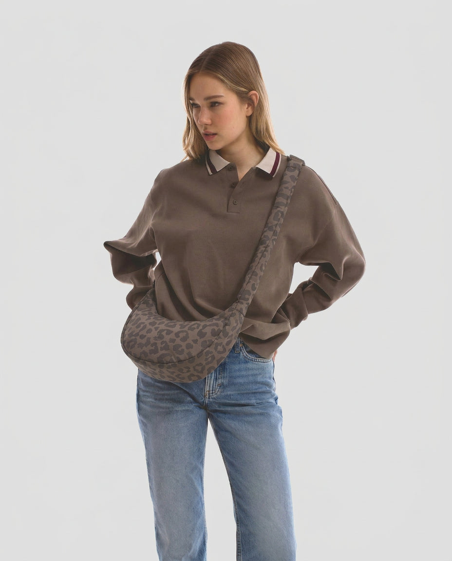 Unser weibliches Model präsentiert sich hier mit der Half-Moon-Bag "Lou Medium" in braun leo. | Bild wurde mit KI geändert