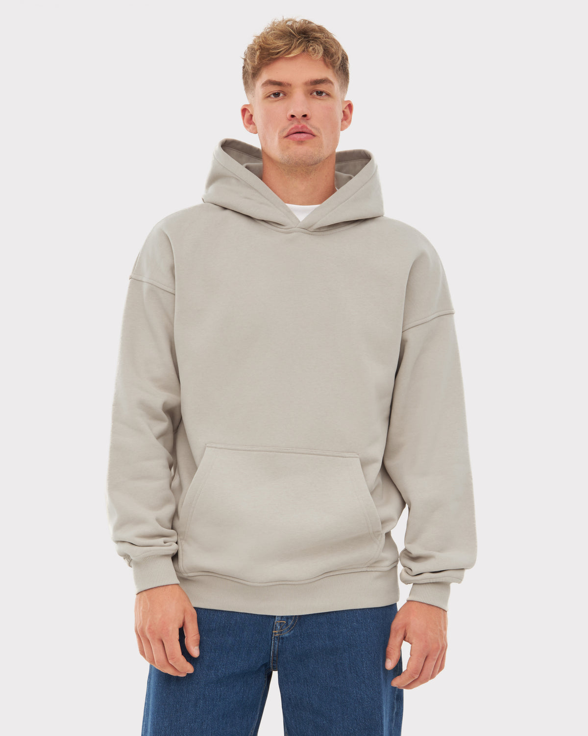 Mann trägt oversized Hoodie 'Cody' in hellem Grau mit Kängurutasche und Kapuze