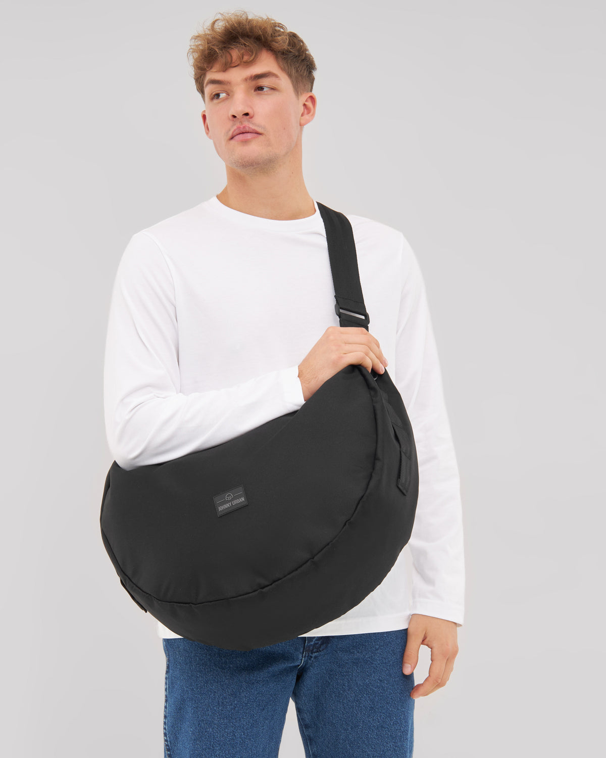 Mann trägt die schwarze Half Moon Bag 'Ally XL' von Johnny Urban quer über die Schulter