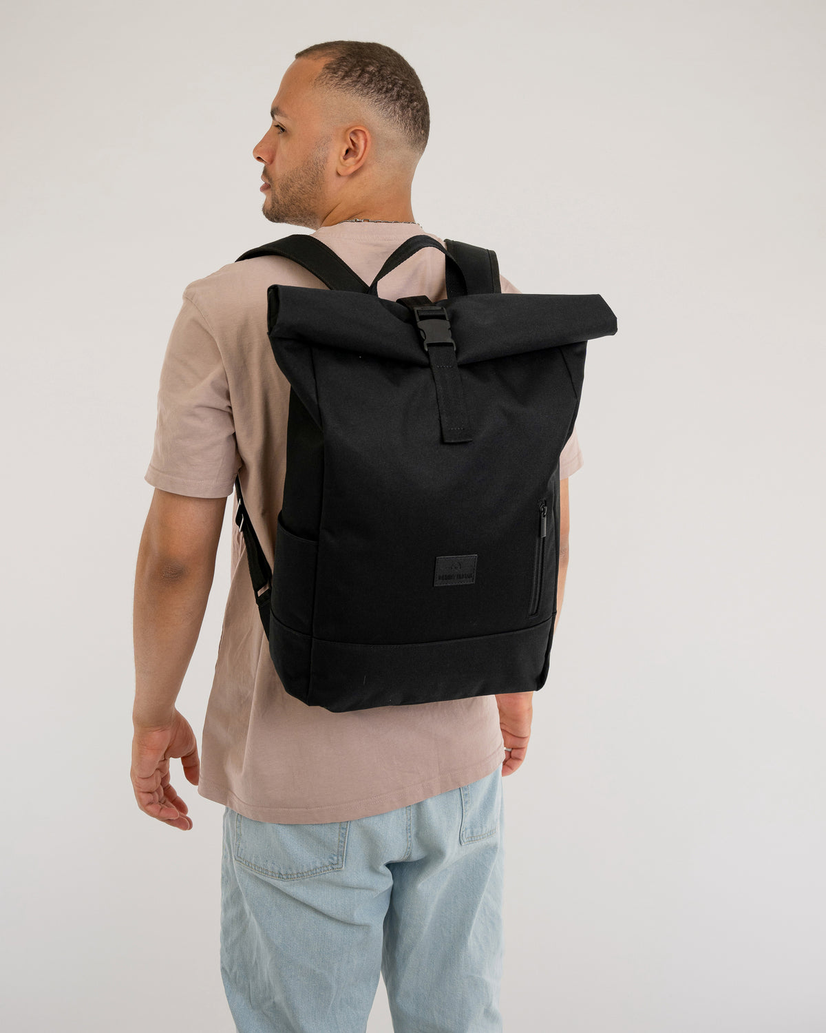 Mann von hinten mit Rolltop Rucksack 'Robin Large' in Schwarz an den Schultern