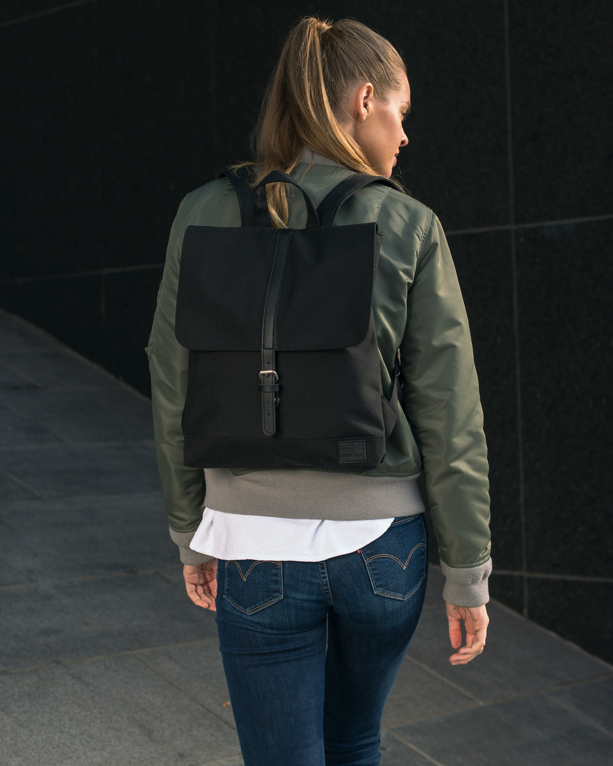 Frau trägt schwarzen Rucksack 'Mia' von Johnny Urban, umgeben von urbaner Kulisse