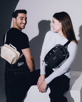 Mann mit schwarzer Umhängetasche und Frau mit schwarzer Lenkertasche Fahrrad 'Nelson' lächeln sich an