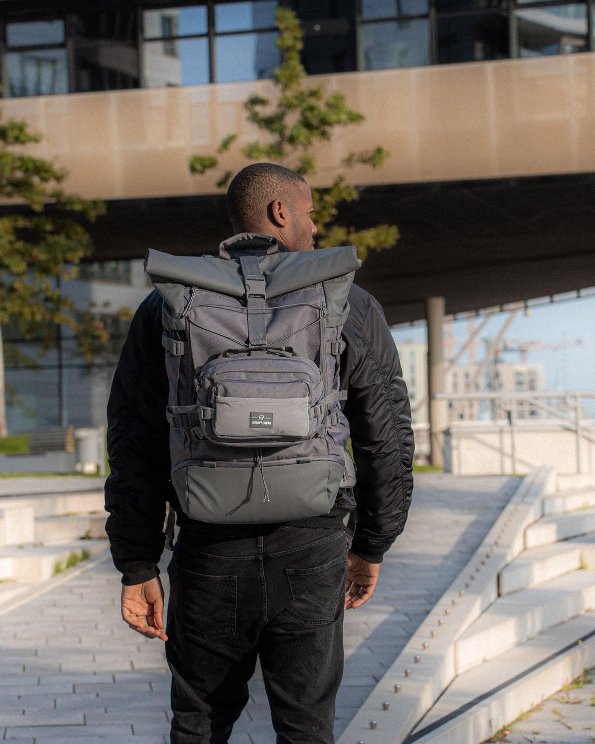 Ein Mann steht mit dem Allen XL Travel Rucksack vor der Hafencity Universität in Hamburg 