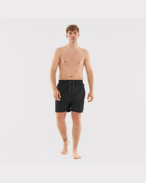 Mann trägt schwarze Badehose 'Jay' mit Kordelzug, frontal stehend, barfuß