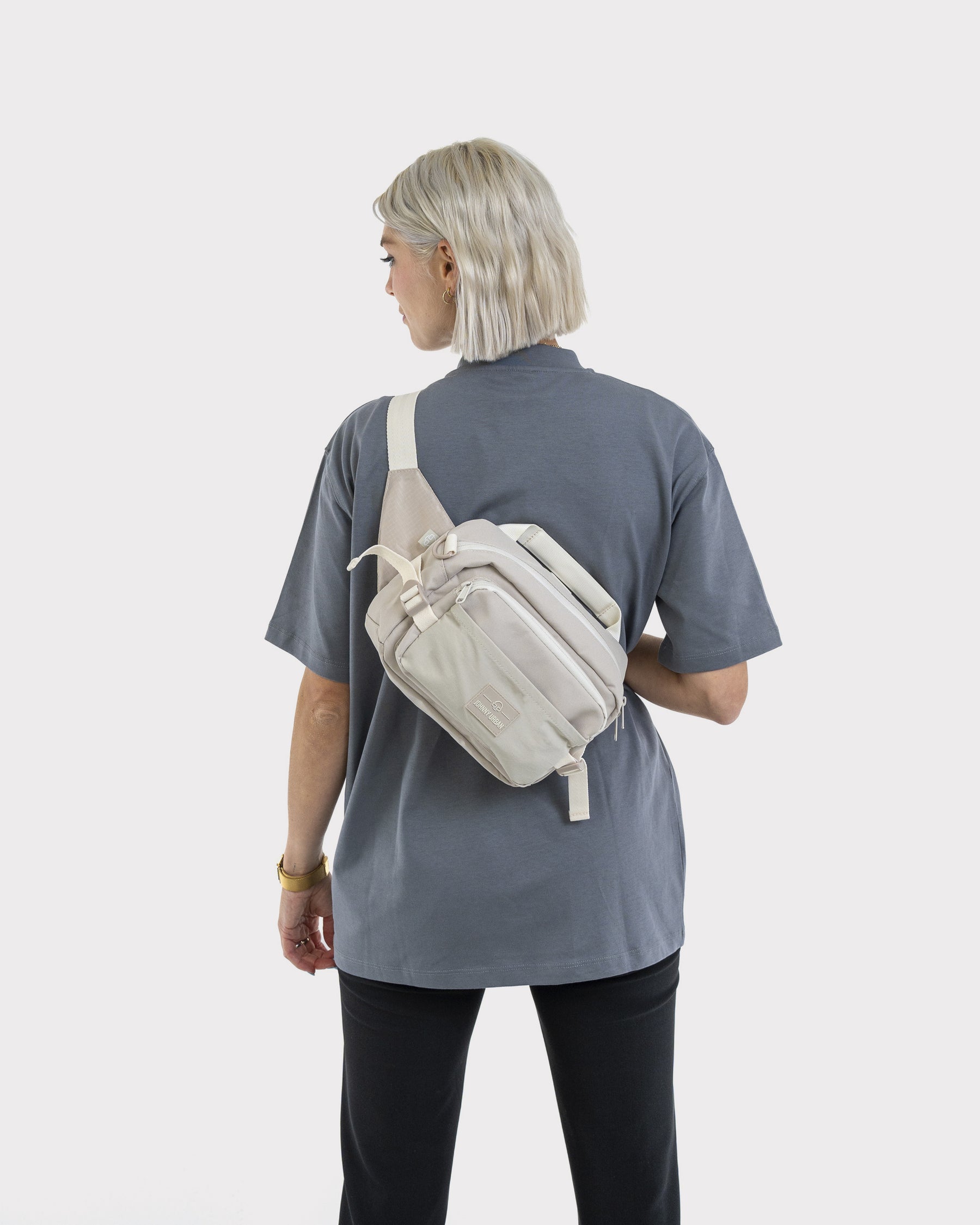 Frau von hinten mit kurzer, blonder Frisur trägt beige Bauchtasche 'Travis' quer über den Rücken
