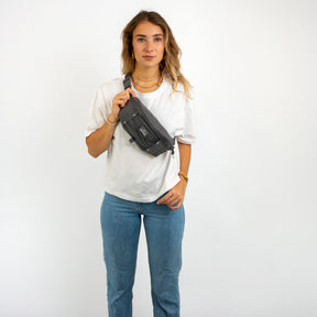 Frau trägt graue Bauchtasche 'Devin' von Johnny Urban über weißem T-Shirt und blauen Jeans
