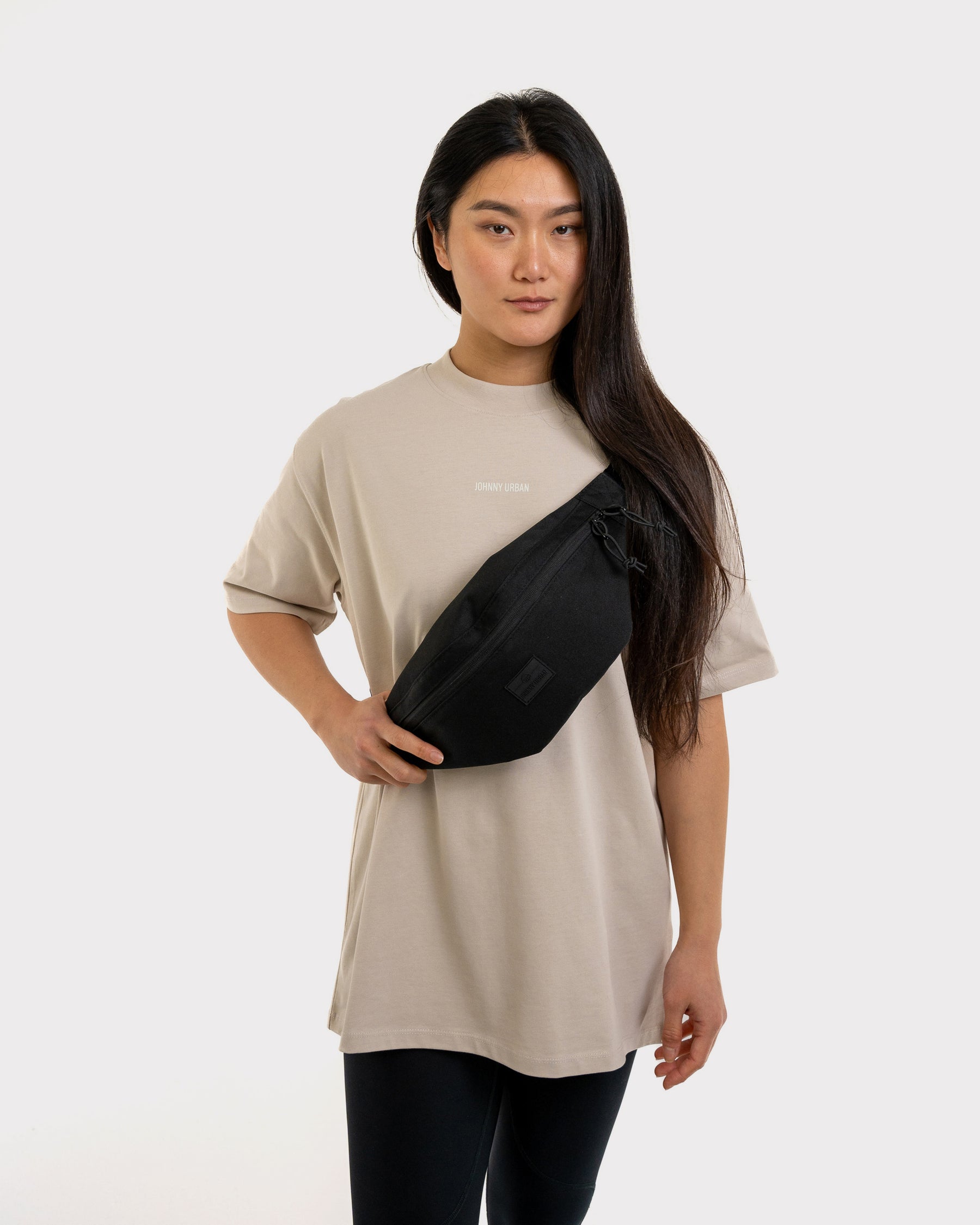 Frau trägt große schwarze Johnny Urban Bauchtasche 'Erik Large' quer über der Brust mit beige T-Shirt