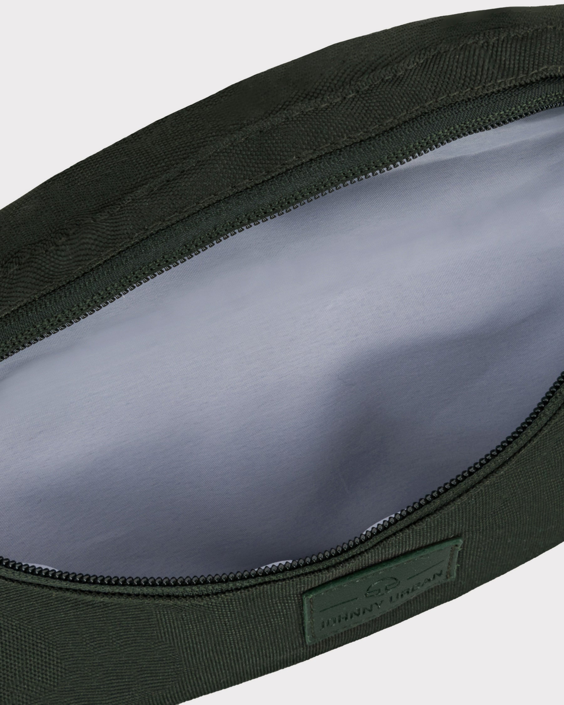 Geöffneter Reißverschluss einer grünen Bauchtasche 'Erik Small' von Johnny Urban mit grauem Innenfutter