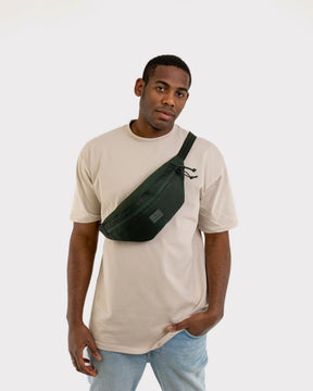 Mann trägt dunkelgrüne Johnny Urban Bauchtasche 'Erik Large' quer über die Brust mit beige T-Shirt und Jeans
