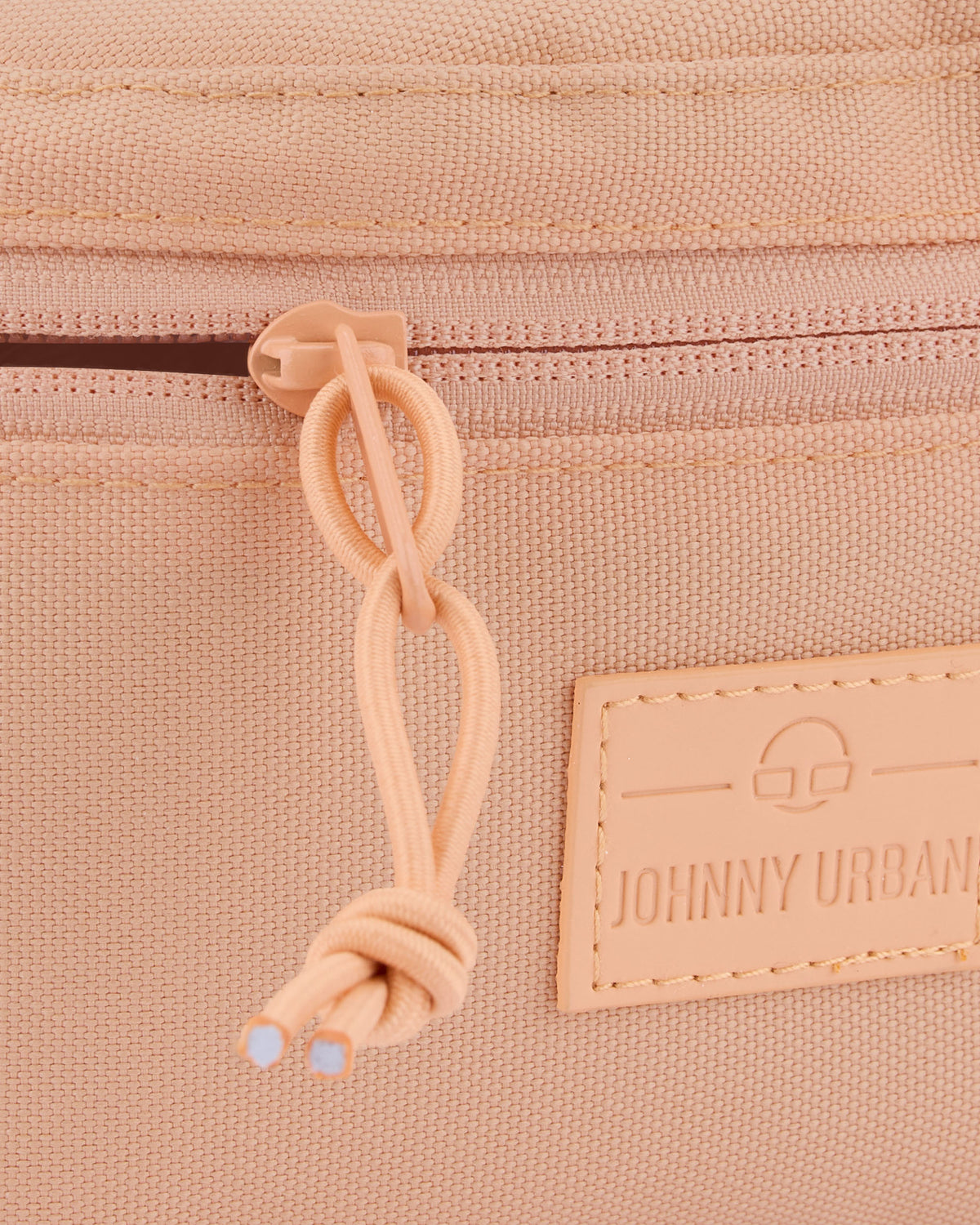 Detailansicht des Reißverschlusses und des Lederlogos der Johnny Urban Bauchtasche 'Erik Small' in Pfirsichfarben