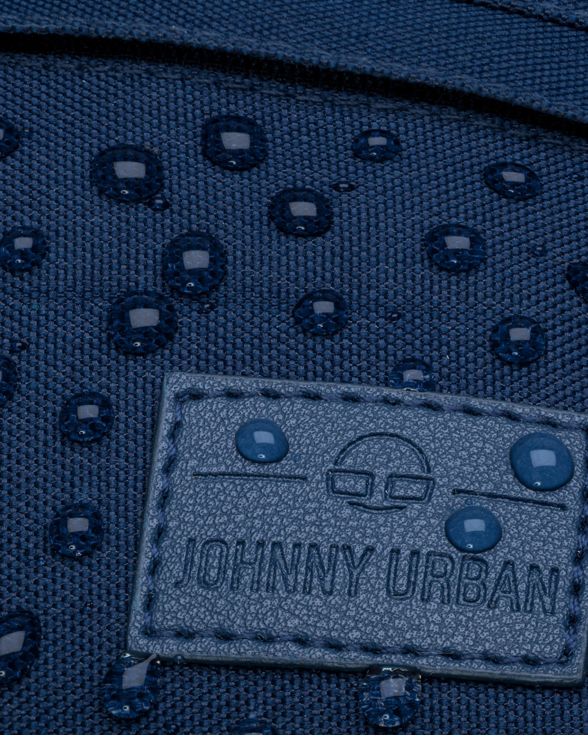 Nahaufnahme einer blauen, wasserabweisenden Bauchtasche 'Tom' von Johnny Urban mit Wassertropfen