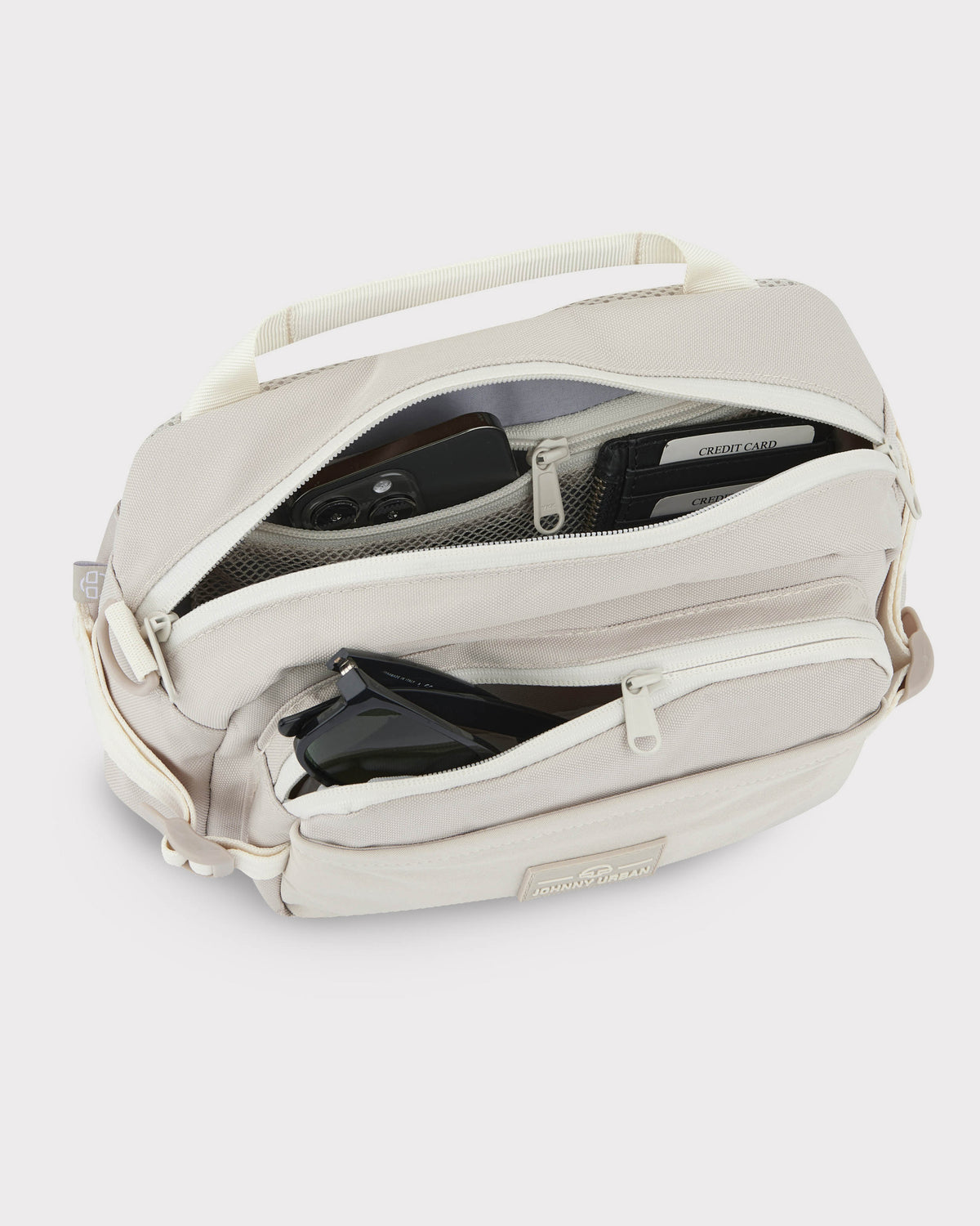Beige Bauchtasche 'Travis' von Johnny Urban mit mehreren Reißverschlussfächern, gefüllt mit Smartphone, Sonnenbrille und Kreditkartenetui