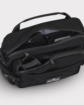 Schwarze Bauchtasche 'Travis' von Johnny Urban mit geöffneten Reißverschlusstaschen, darin Smartphone, Kreditkarte und Sonnenbrille