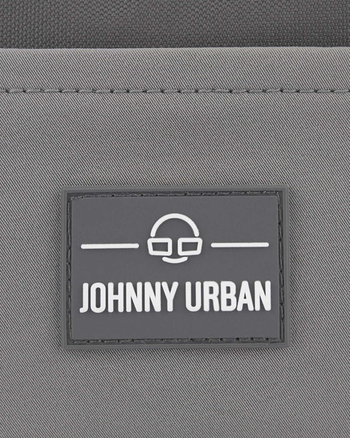 Graues Logo mit dem Text 'Johnny Urban' auf der nachhaltigen Bauchtasche 'Travis'