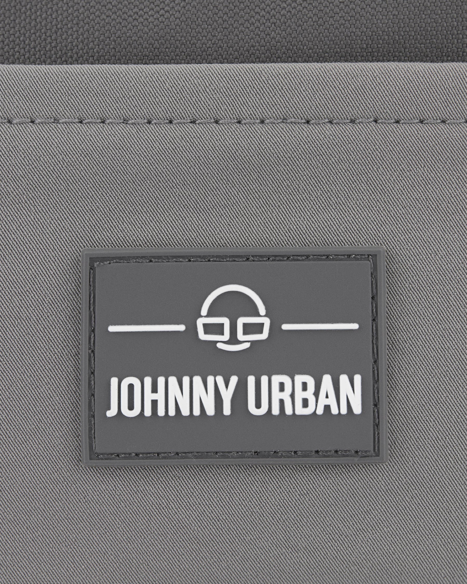 Graues Logo mit dem Text 'Johnny Urban' auf der nachhaltigen Bauchtasche 'Travis'
