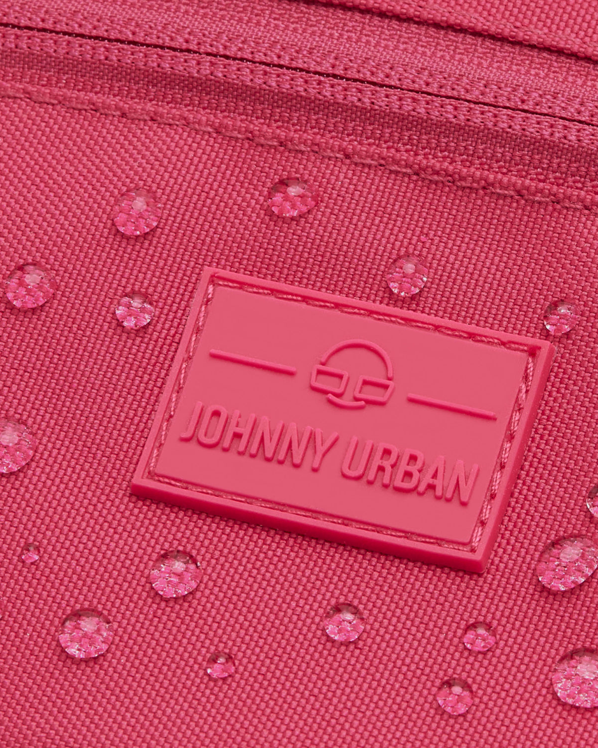 Nahaufnahme der wasserabweisenden pinkfarbenen Bauchtasche 'Ben' von Johnny Urban mit Logo-Patch und Wassertropfen