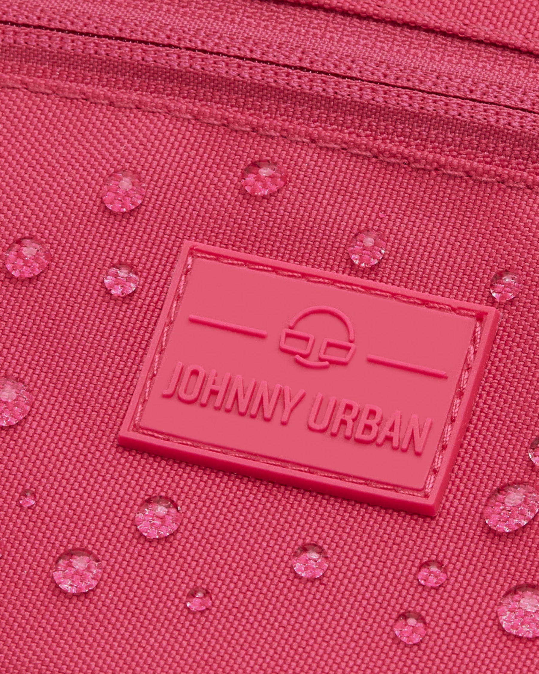 Nahaufnahme der wasserabweisenden pinkfarbenen Bauchtasche 'Ben' von Johnny Urban mit Logo-Patch und Wassertropfen