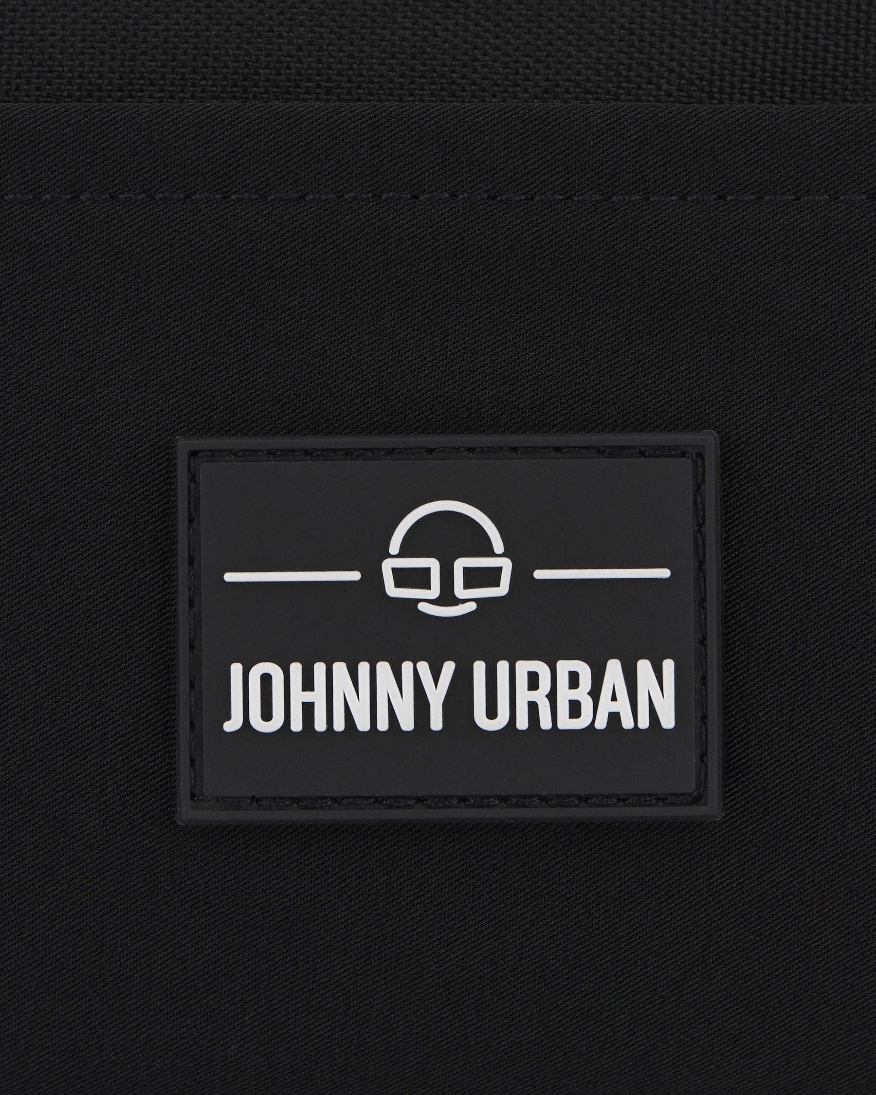 Schwarzes Logoetikett mit weißem Johnny Urban Schriftzug und minimalistischer Brillen-Motiv auf Stoff
