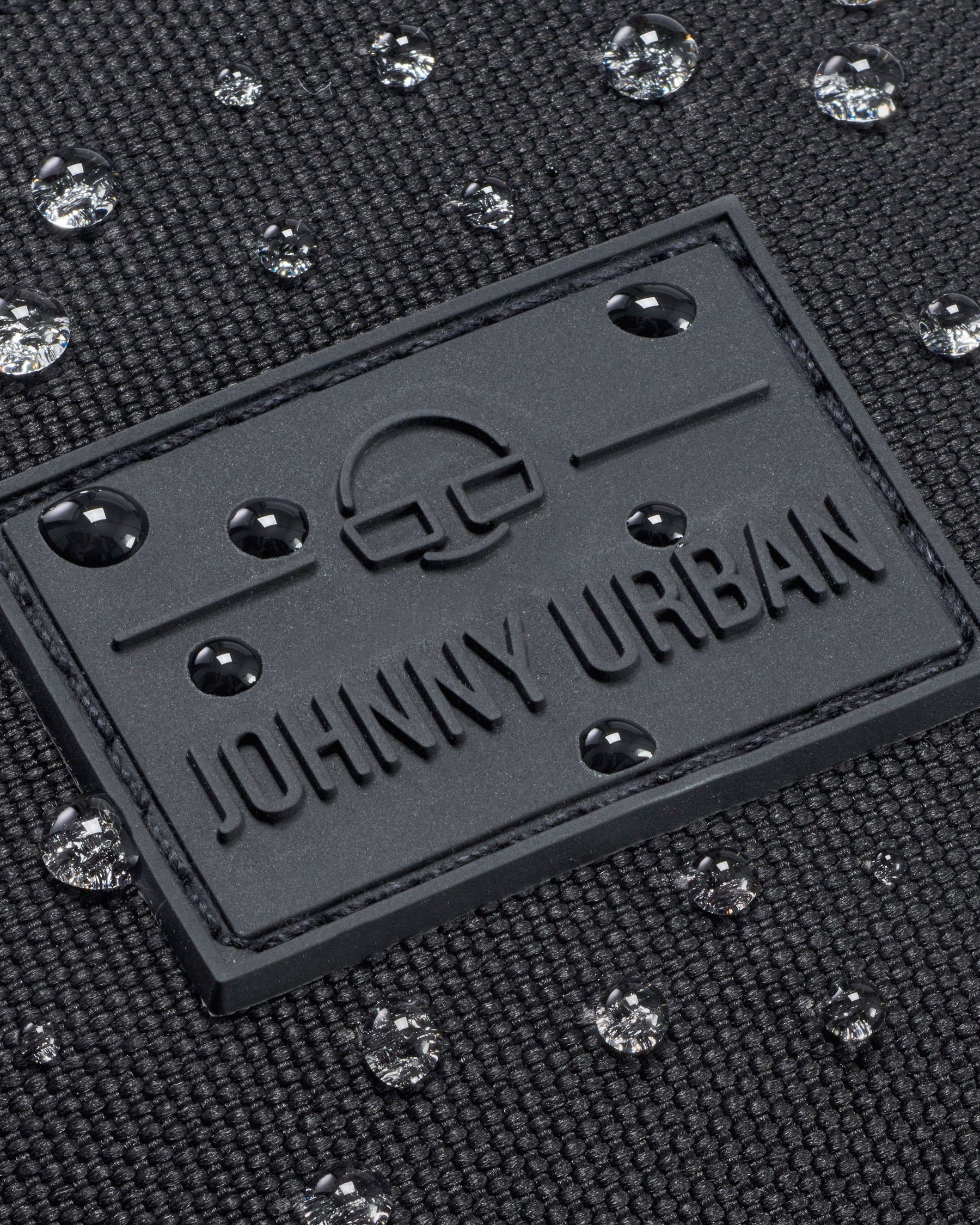 Nahaufnahme der wasserdichten schwarzen Bauchtasche 'Erik Large' von Johnny Urban mit Wasserperlen auf der Oberfläche