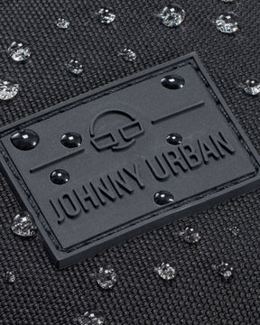 Nahaufnahme der wasserdichten schwarzen Bauchtasche 'Erik Large' von Johnny Urban mit Wasserperlen auf der Oberfläche