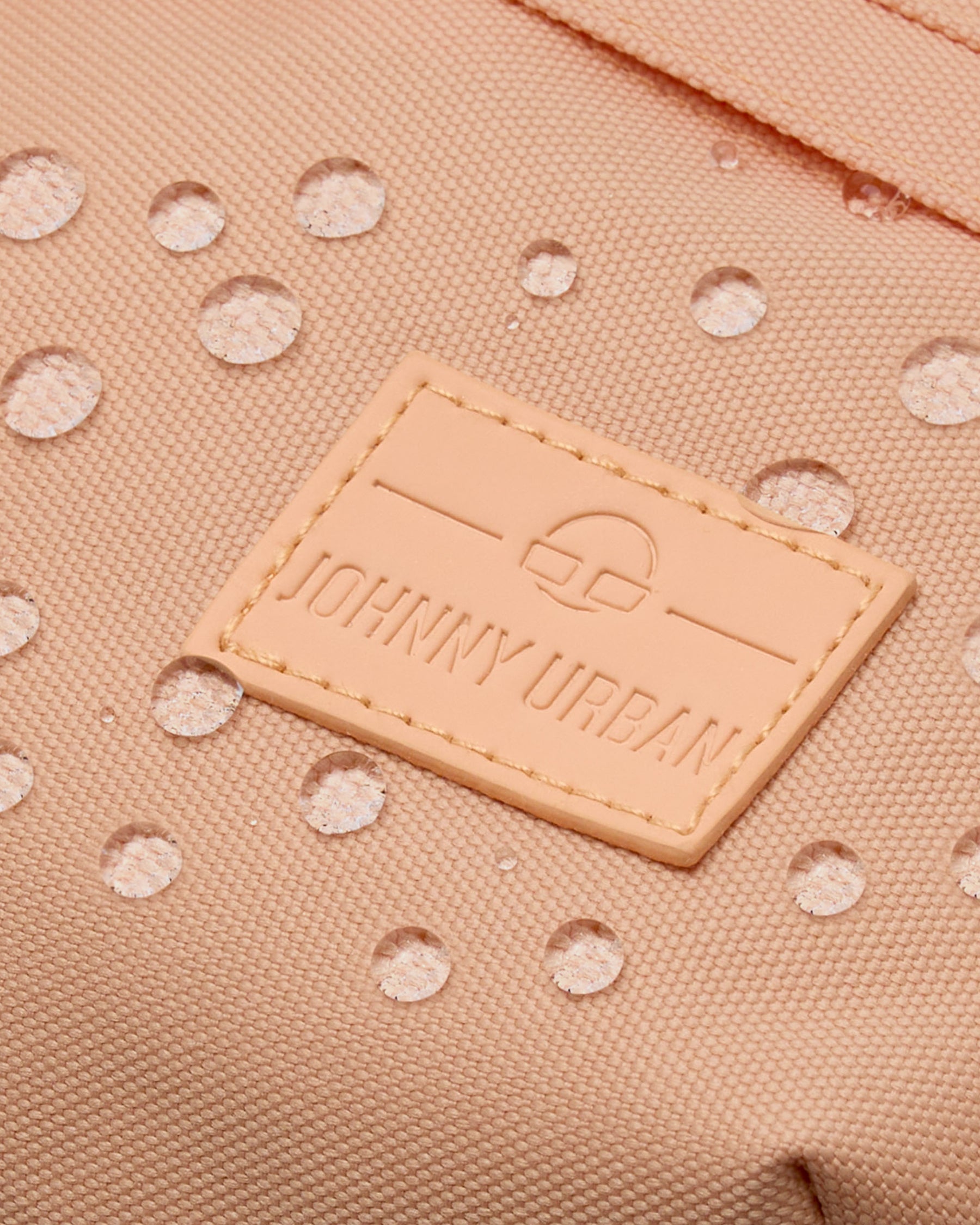 Nahaufnahme der wasserabweisenden, pfirsichfarbenen Bauchtasche 'Tom' mit aufgenähtem Johnny Urban Logo
