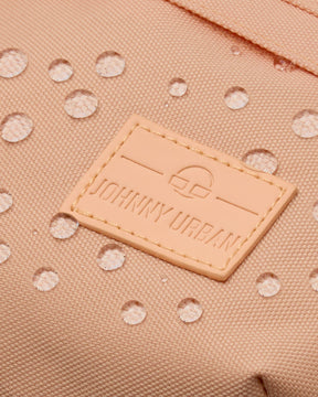 Nahaufnahme der wasserabweisenden, pfirsichfarbenen Bauchtasche 'Tom' mit aufgenähtem Johnny Urban Logo