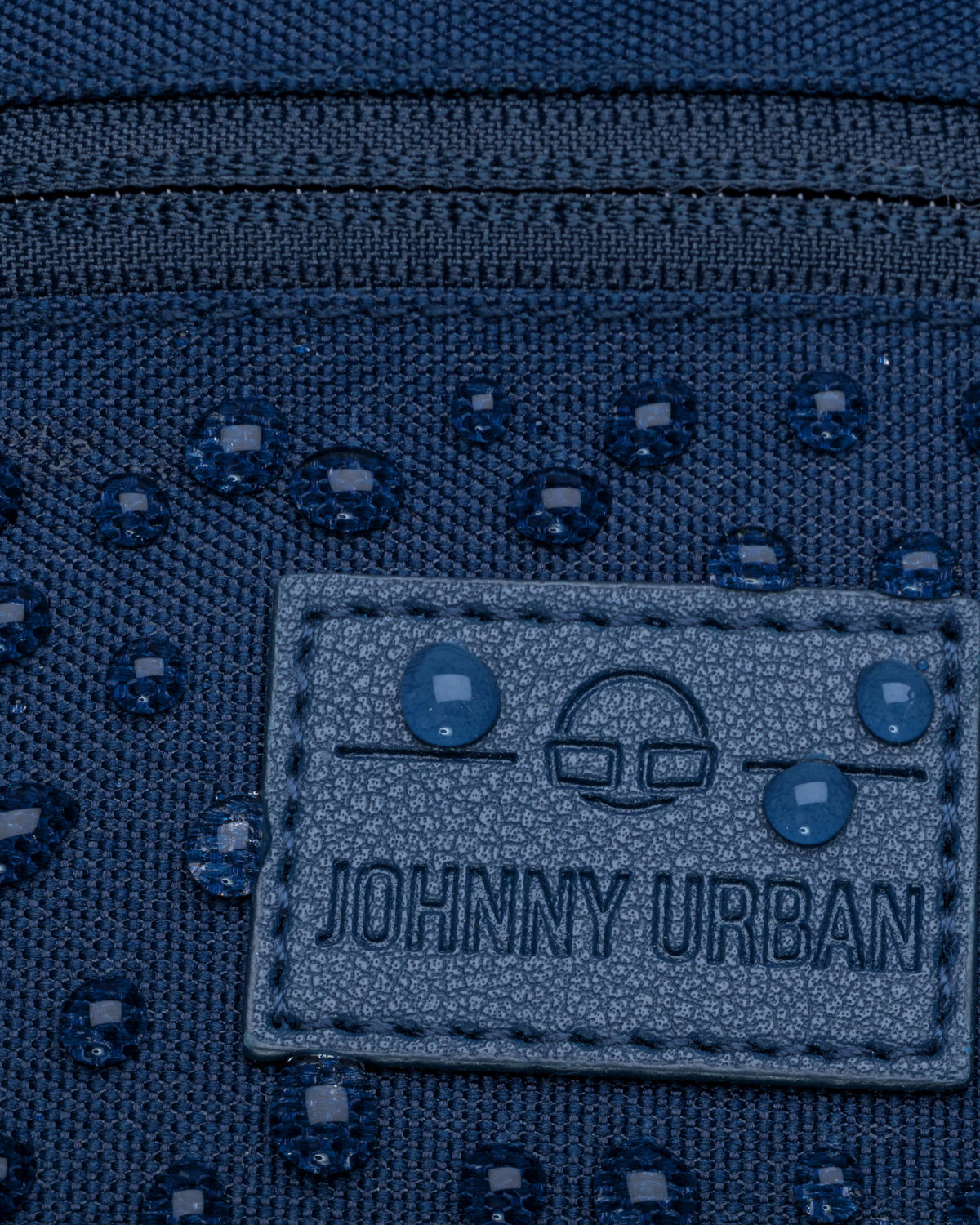 Detailaufnahme der wasserabweisenden blauen Bauchtasche „Erik Small“ von Johnny Urban mit sichtbaren Wassertropfen und Markenlabel