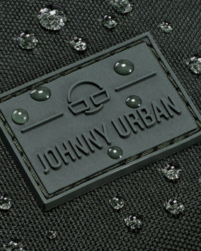 Gummilogo mit Schriftzug 'Johnny Urban' auf wasserabweisendem dunkelgrünem Stoff mit Wassertropfen