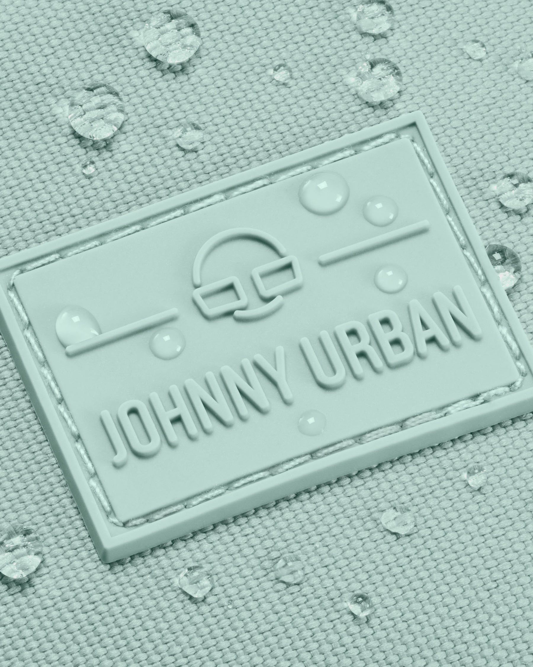 Nahaufnahme des wasserabweisenden Johnny Urban Logos auf der mintfarbenen Bauchtasche 'Erik Large' mit Wassertropfen