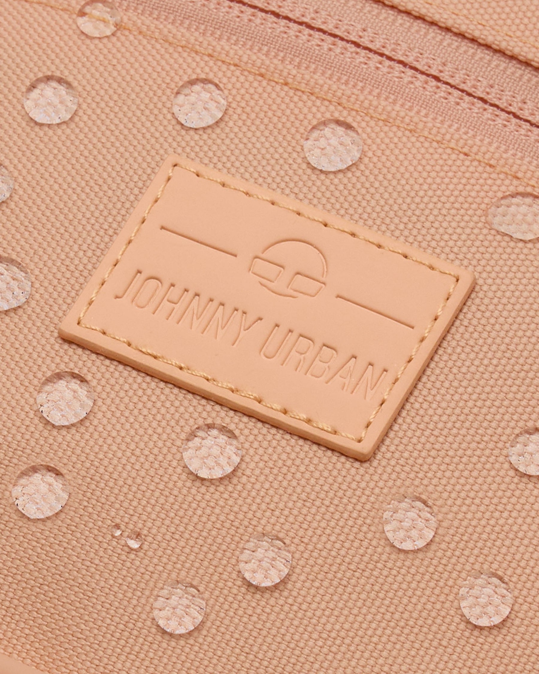 Nahaufnahme der wasserabweisenden Bauchtasche 'Ben' von Johnny Urban in Pfirsichfarbe mit sichtbaren Wassertropfen