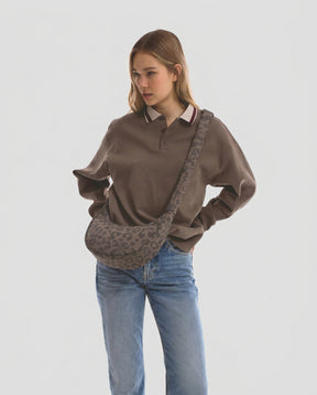Unser weibliches Model präsentiert sich hier mit der Half-Moon-Bag "Lou Medium" in braun leo. | Bild wurde mit KI geändert