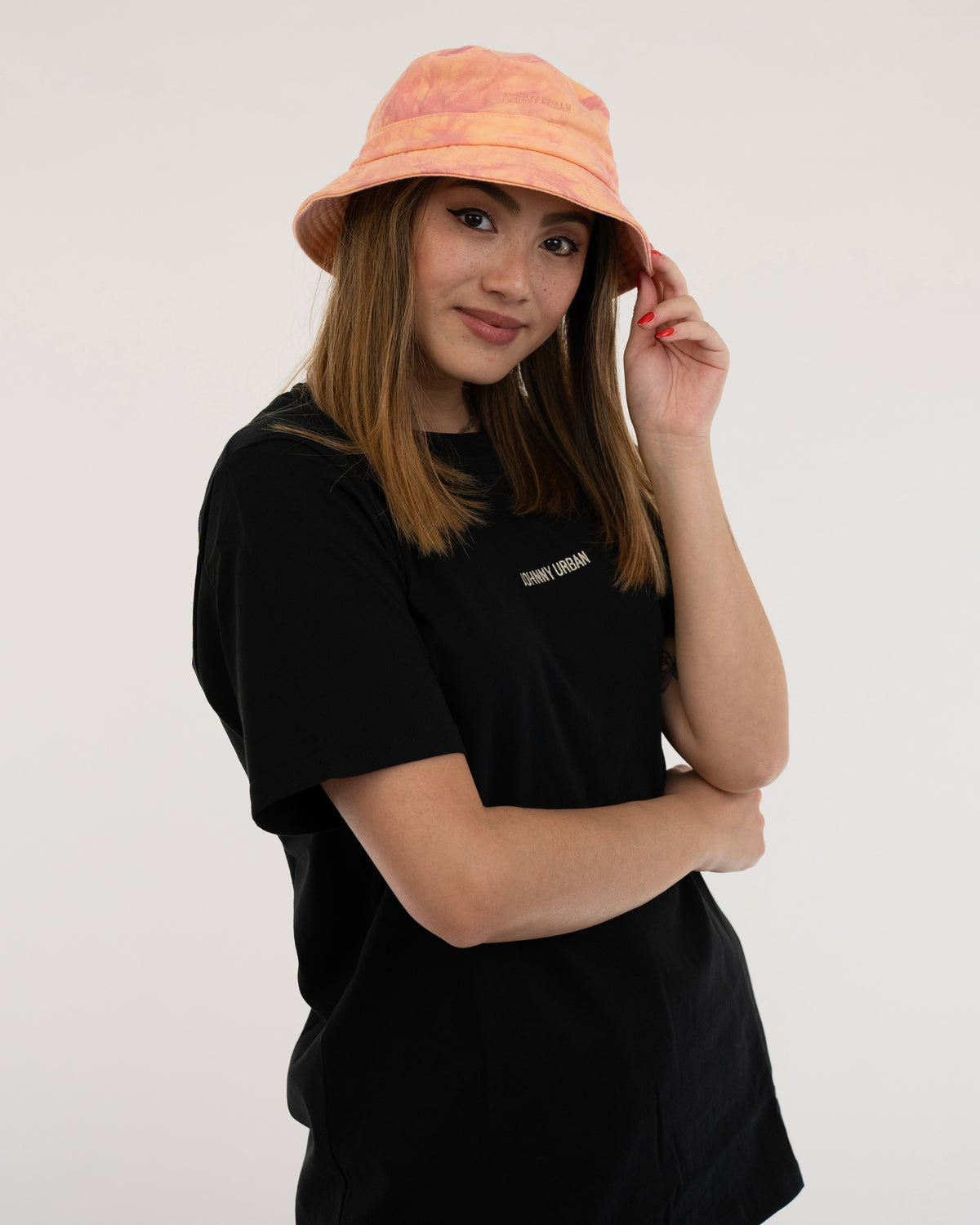 Frau trägt orangefarbenen Bucket Hat 'Gill' und schwarzes T-Shirt mit 'Johnny Urban' Schriftzug