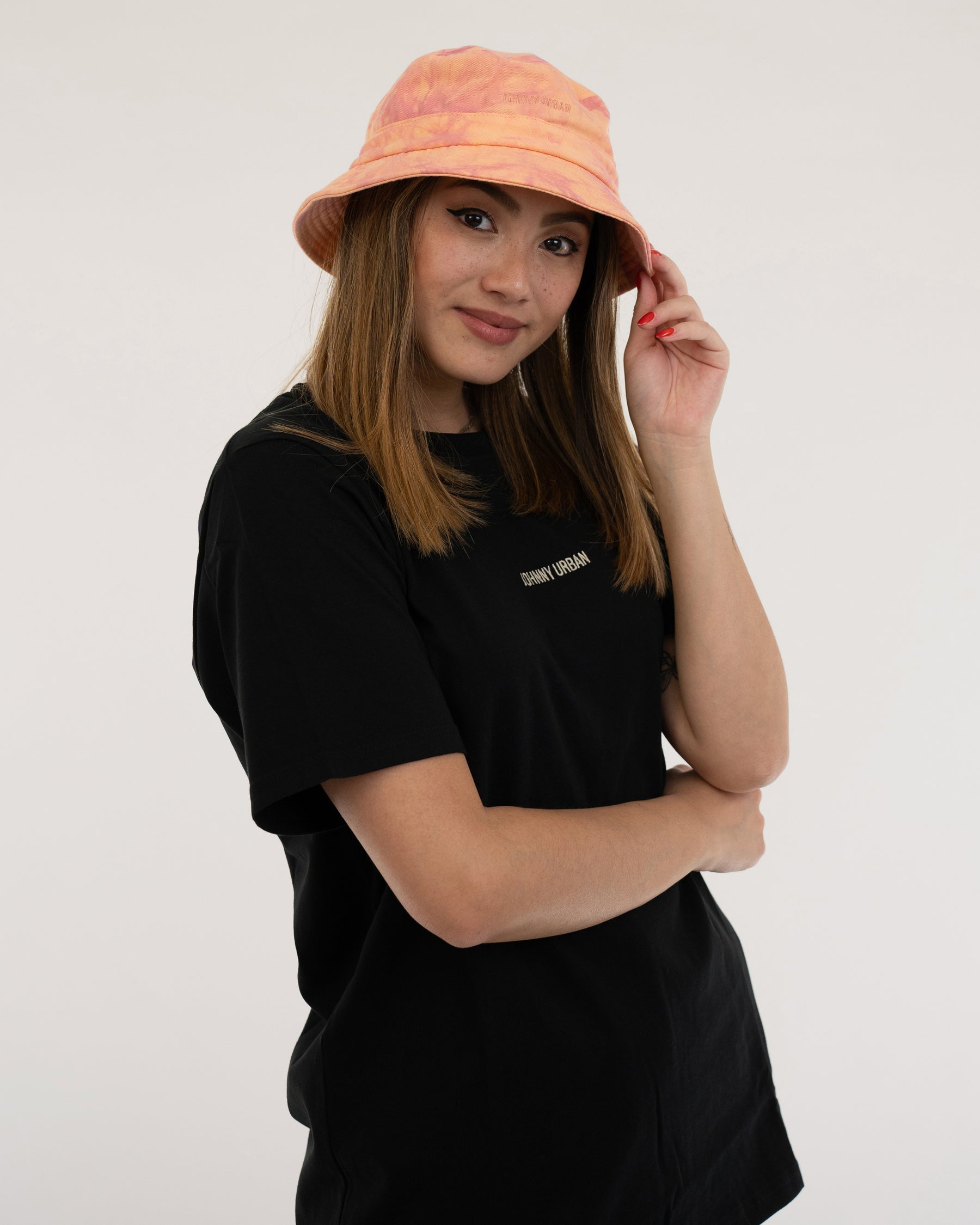 Frau trägt orangefarbenen Bucket Hat 'Gill' und schwarzes T-Shirt mit 'Johnny Urban' Schriftzug