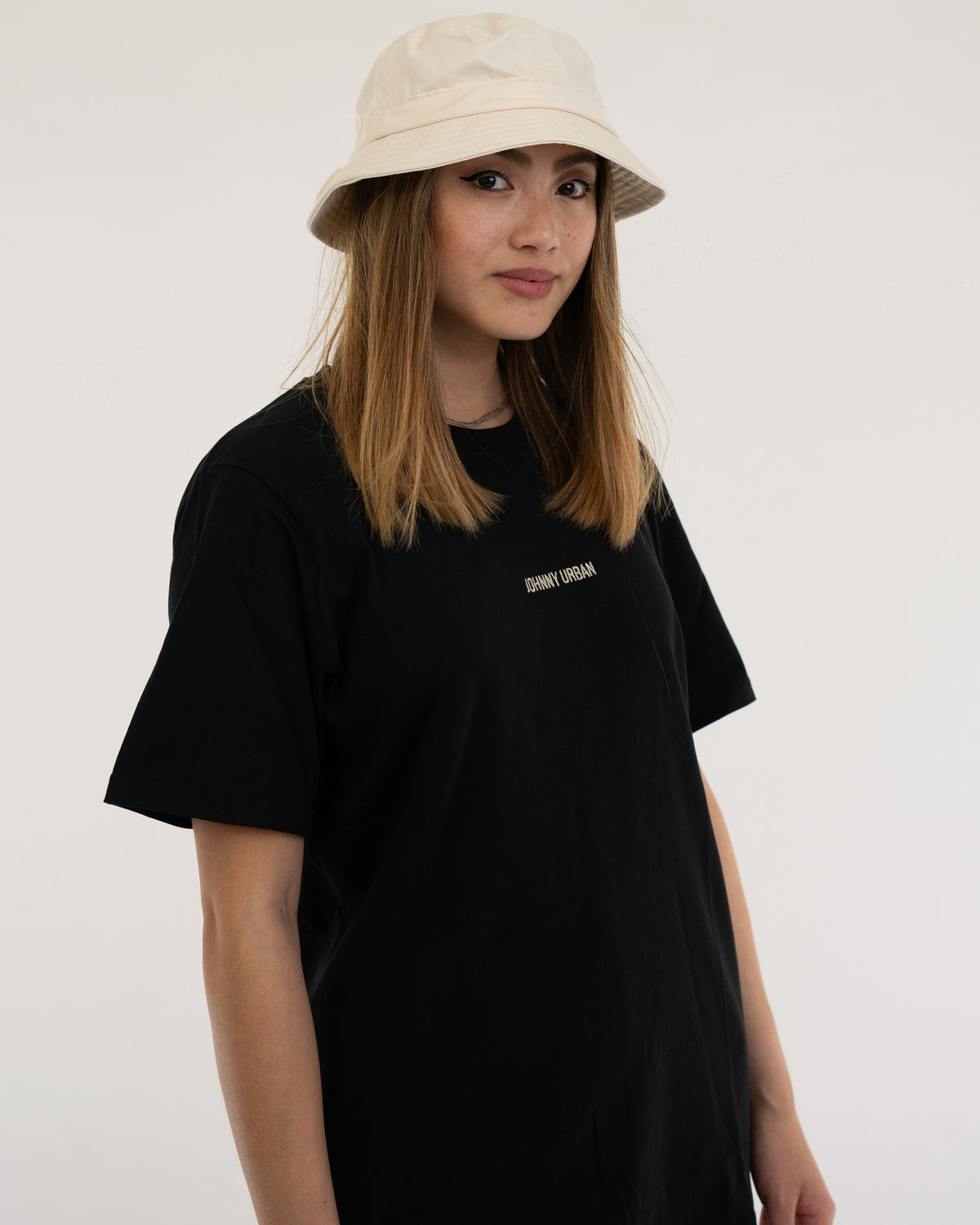Frau trägt beige Bucket Hat 'Gill' und schwarzes T-Shirt mit 'Johnny Urban' Aufschrift