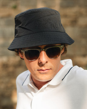 Mann trägt schwarzen Bucket Hat 'Bob' von Johnny Urban und Sonnenbrille, weißes Polohemd