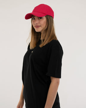 Frau trägt pinke Canvas-Cap 'Jen' und schwarzes T-Shirt, seitliche Ansicht