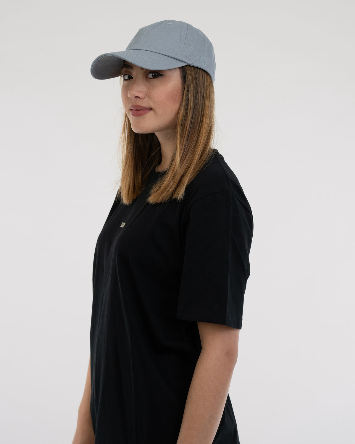 Seitliches Porträt einer Frau mit blaugrauer Cap 'Jen' von Johnny Urban und schwarzem T-Shirt