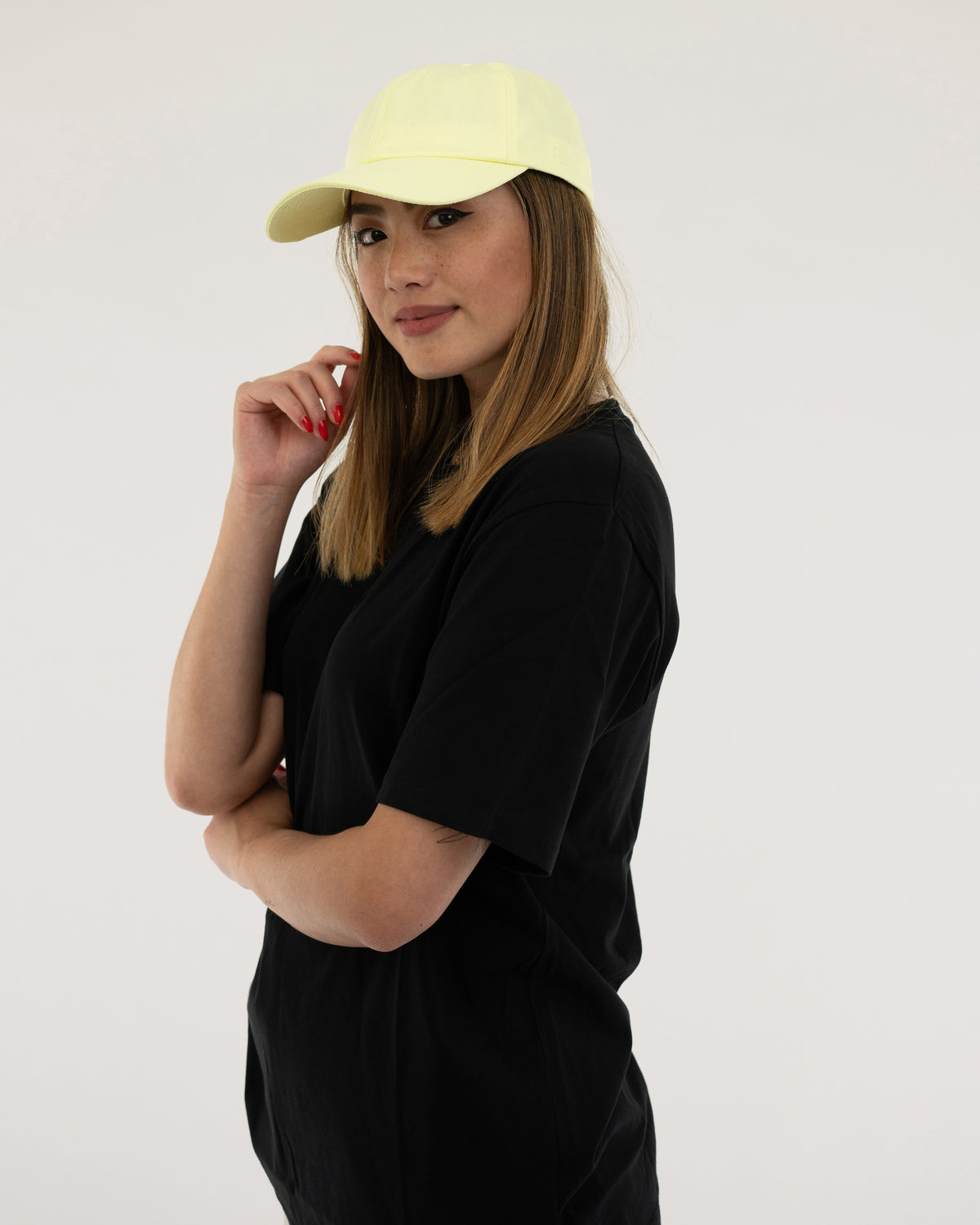 Frau mit schwarzem T-Shirt und lime-gelber Cap 'Jen' schaut zur Seite