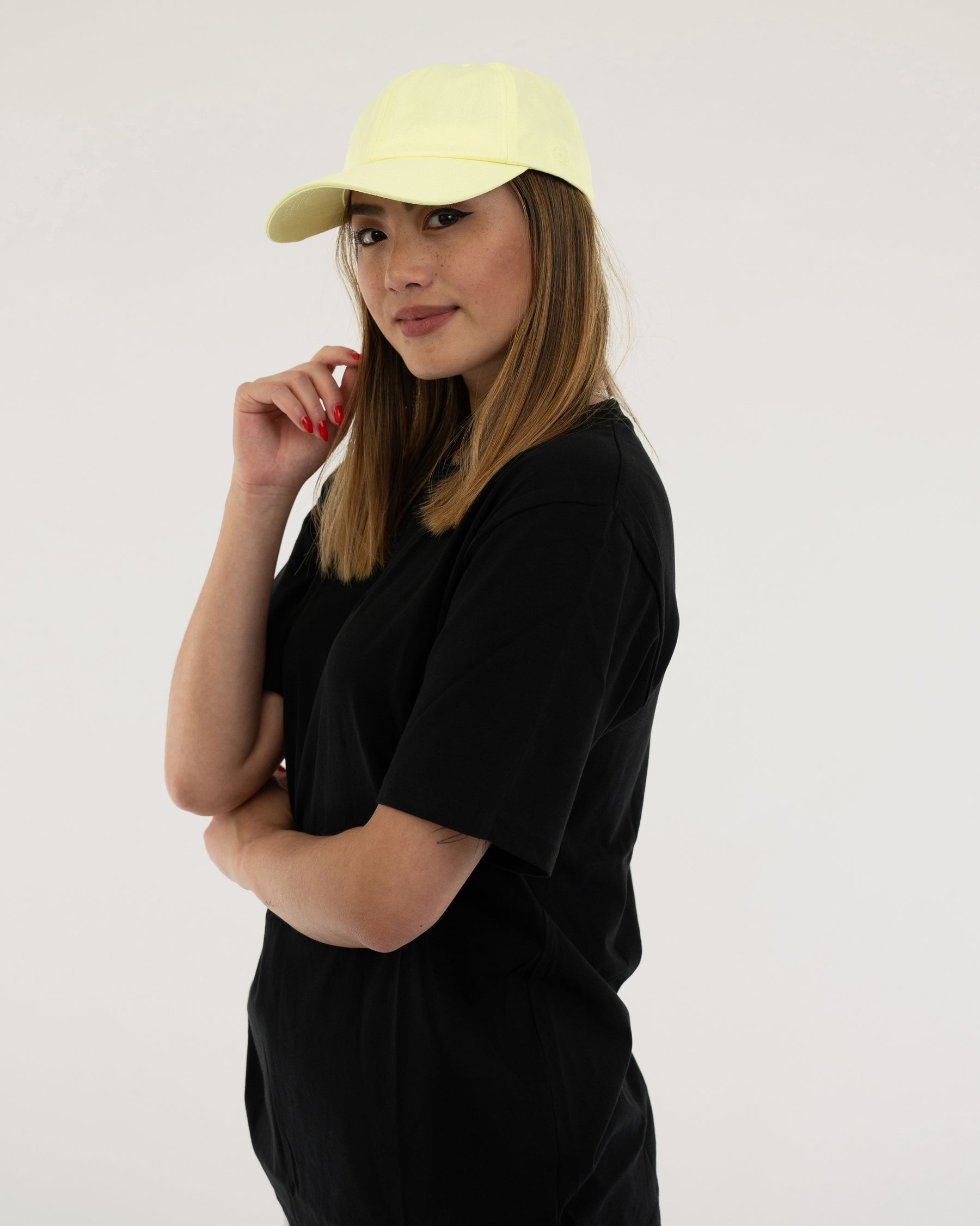 Frau mit schwarzem T-Shirt und lime-gelber Cap 'Jen' schaut zur Seite