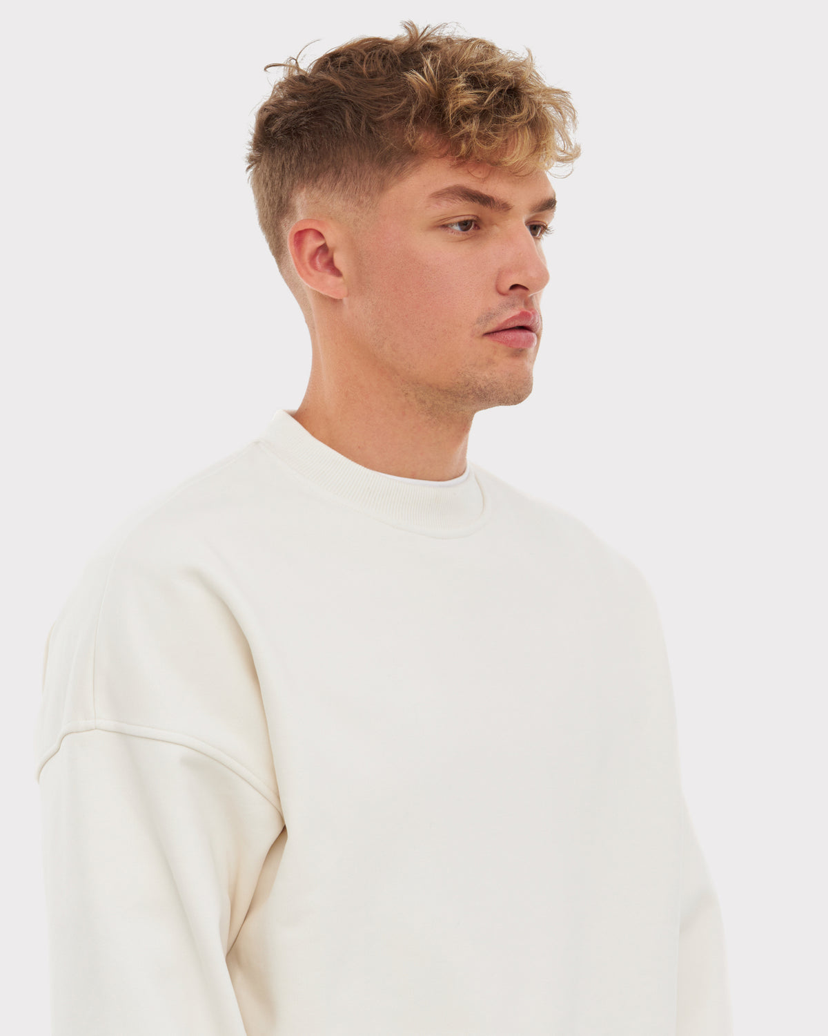 Mann trägt weißen oversized Crewneck 'Carter' von Johnny Urban, stehend im Profil