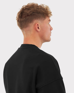Mann von hinten mit kurzem lockigem Haar, trägt Oversized Crewneck 'Carter' Sweatshirt in Schwarz