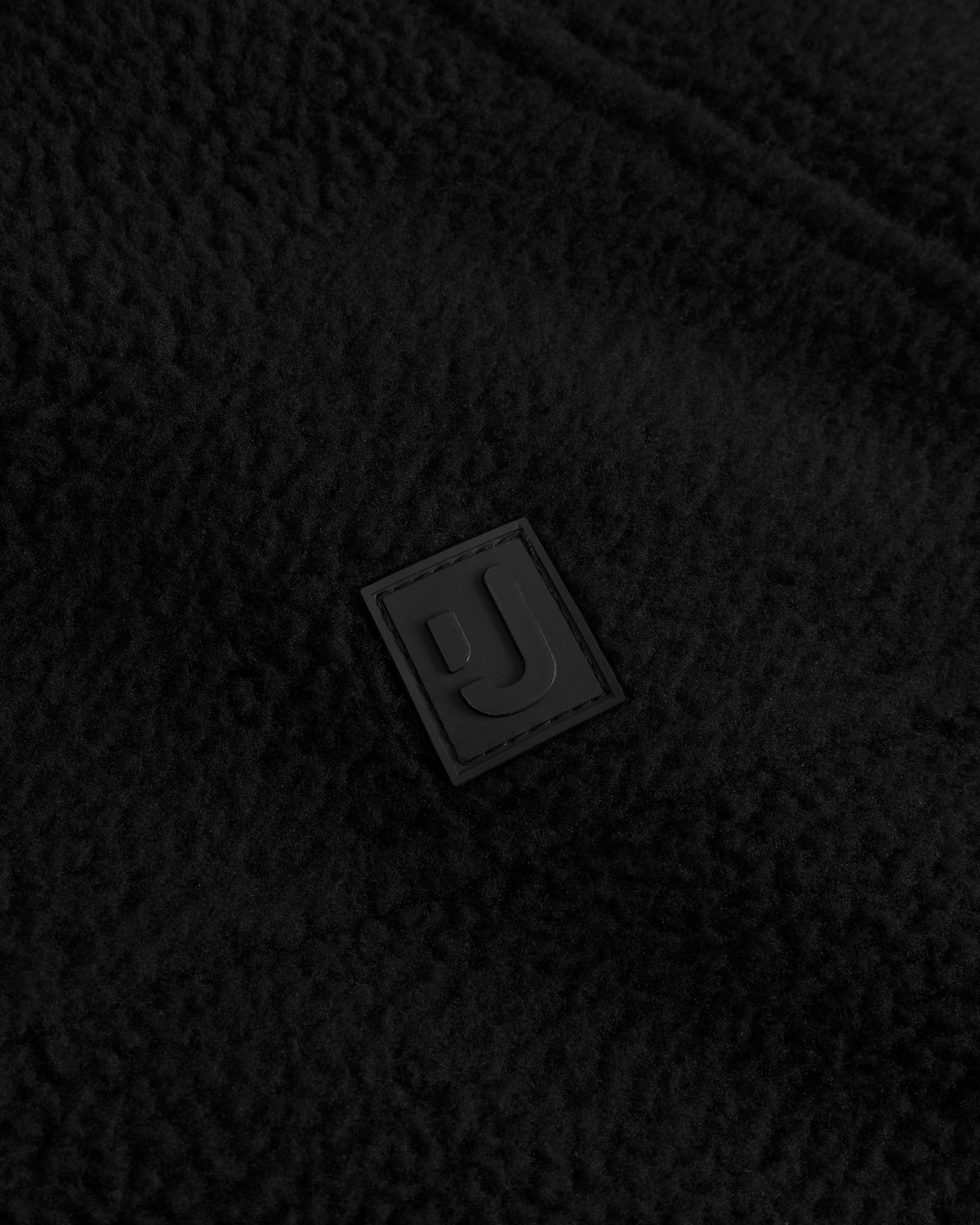 Unser hochwertiges Logo-Badge auf der Fleecejacke Nova in Schwarz. 