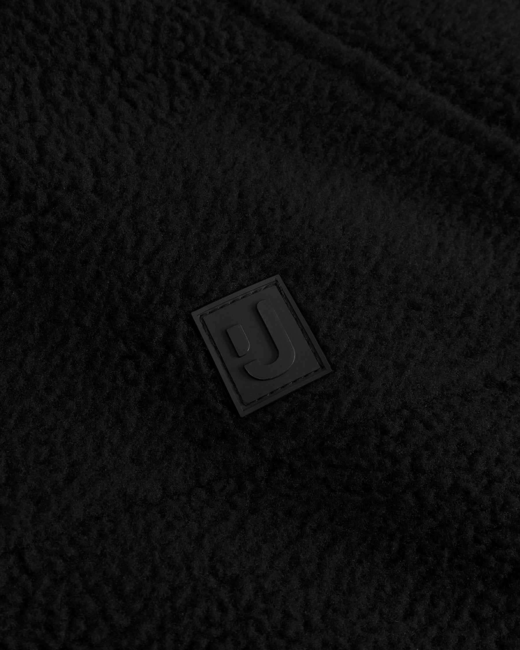 Unser hochwertiges Logo-Badge auf der Fleecejacke Nova in Schwarz. 
