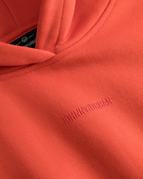 Detailaufnahme eines orangen Cropped Hoodies 'Carly' mit eingeprägtem Schriftzug 'Johnny Urban'