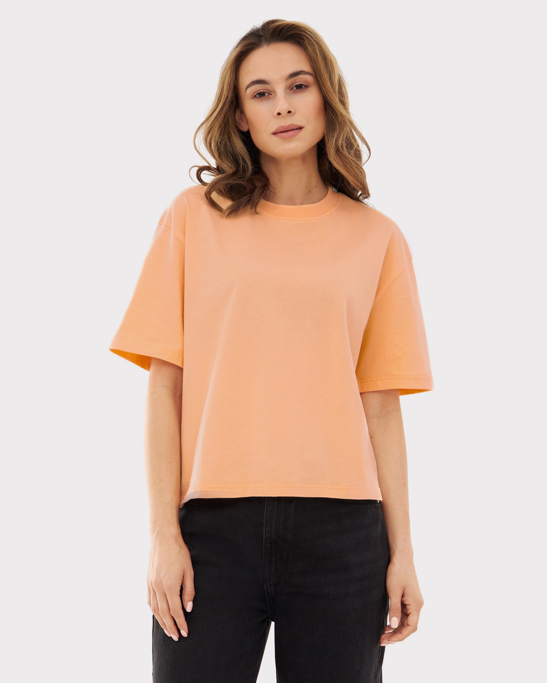 Damen trägt Cropped T-Shirt 'Zoey' in Pfirsich mit kurzen Ärmeln und Rundhalsausschnitt