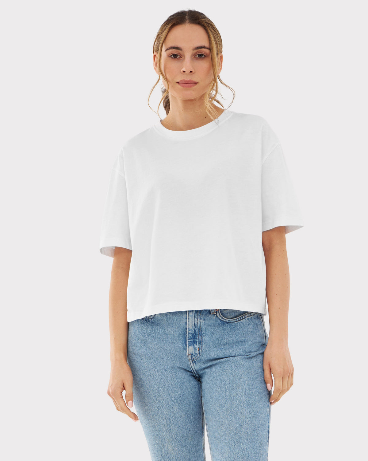 Frau trägt weißes, kurz geschnittenes T-Shirt 'Zoey' und blaue Jeans