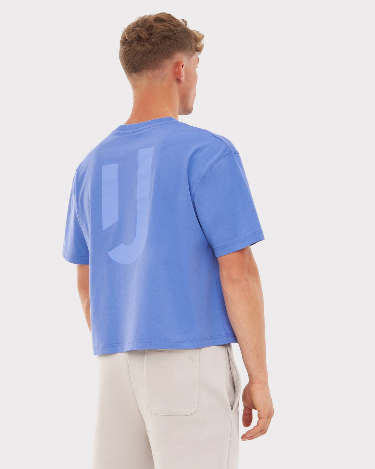 Mann von hinten trägt blau-lila Cropped T-Shirt 'Zoey JU' mit oversized Schnitt und kurzem Ärmel