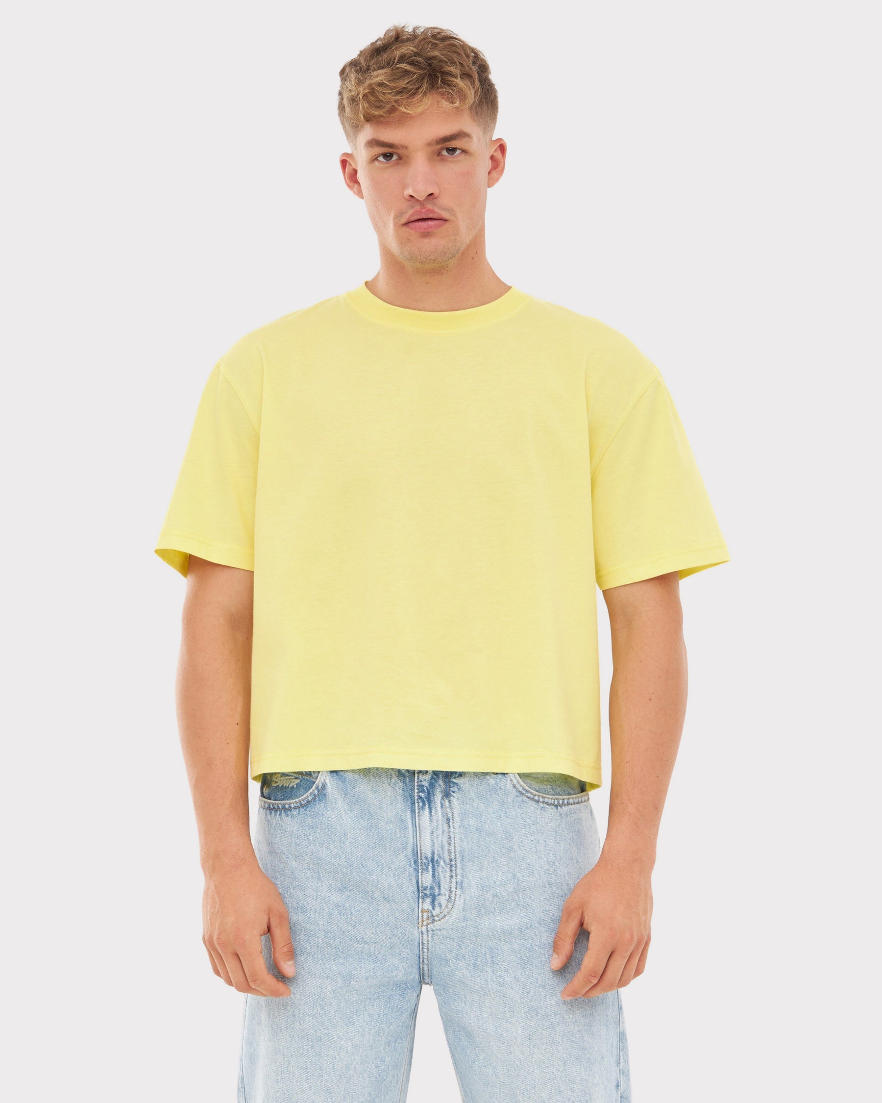 Männliches Modell trägt gelbes Cropped T-Shirt 'Zoey JU' und helle Jeans