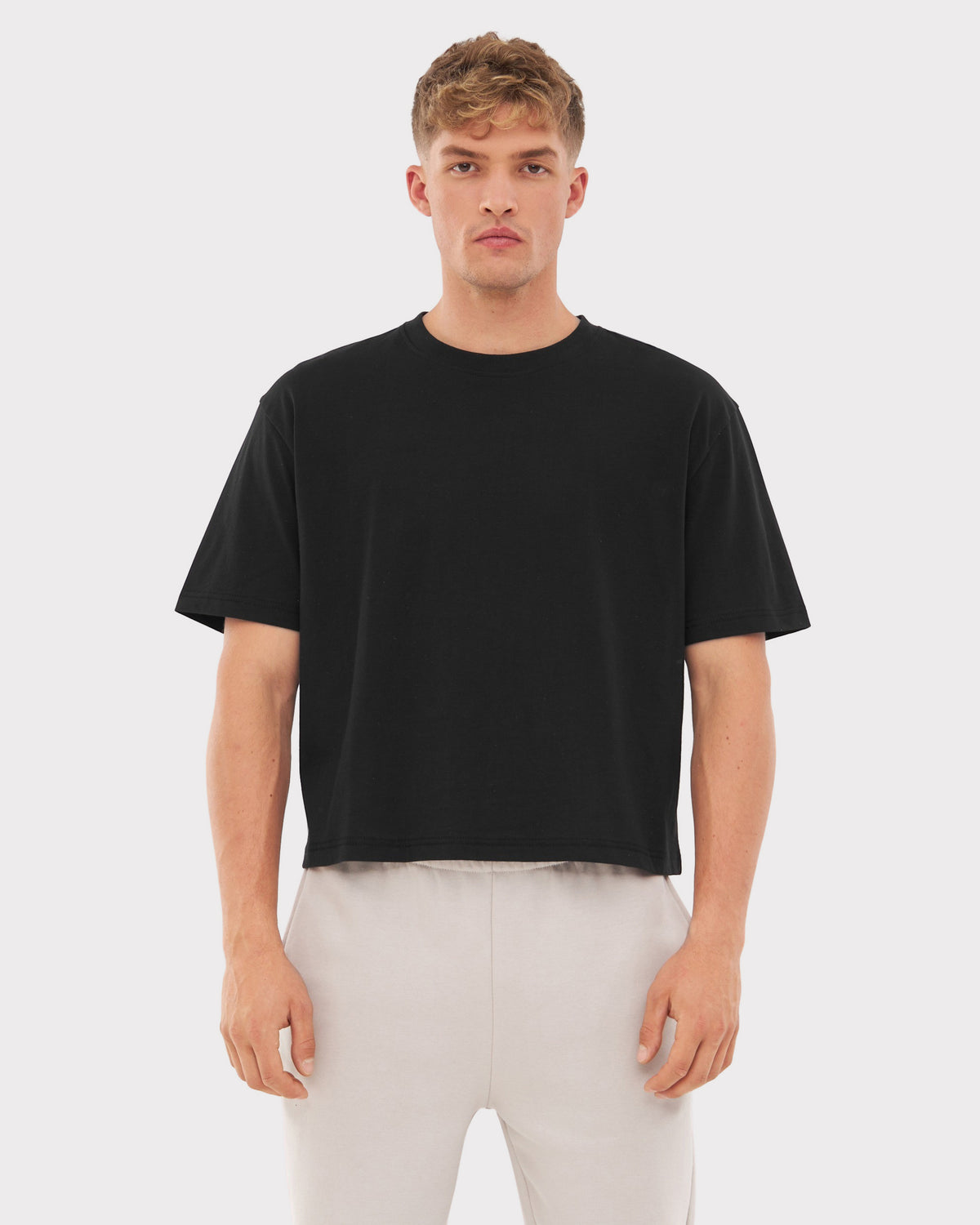 Mann trägt schwarzes Cropped T-Shirt 'Zoey' und helle Hose