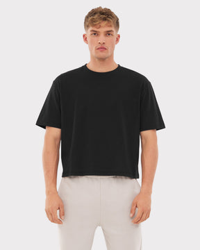 Mann trägt schwarzes Cropped T-Shirt 'Zoey' und helle Hose